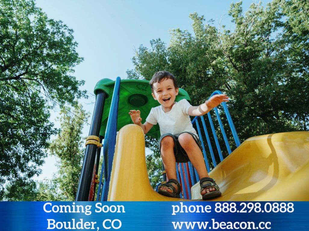 Smiling young boy sliding down yellow slide