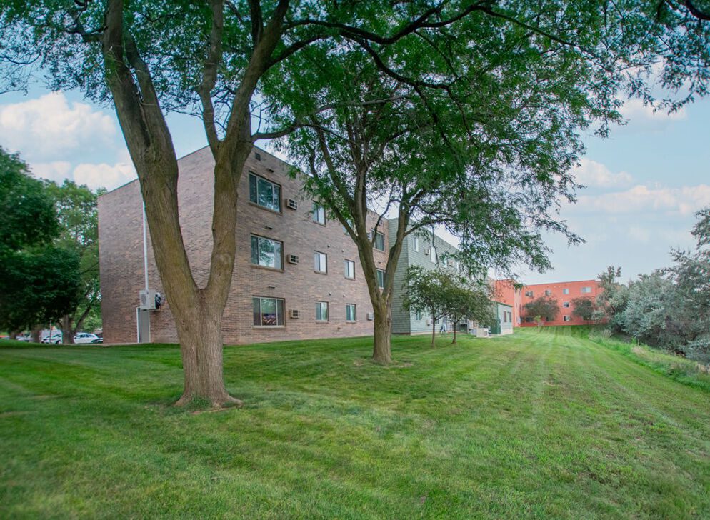Brick apartment building with lawn and trees