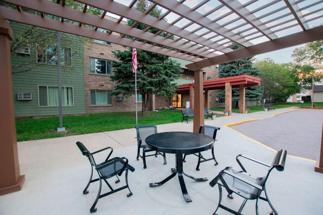 Outdoor seating under pergola near building entrance